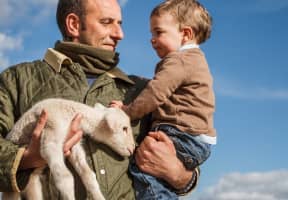 Ganadero con su hijo y un cordero en brazos